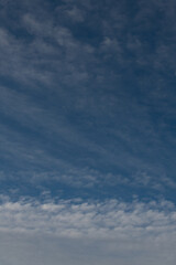 Obraz premium vertical backdrop of blue sky with wispy clouds on top of puffy clouds at bottom nice day looking up climate change weather or environmental vertical format backdrop background or wallpaper 