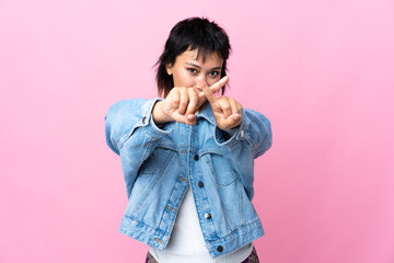 Young Uruguayan woman over isolated pink background making stop gesture with her hand to stop an act