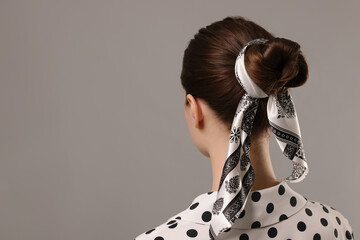Woman with stylish bandana on light grey background, back view. Space for text