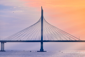 Cable - stayed bridge over the bay in the rays of the sun .  Waterscape at sunset .