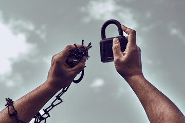 Men's hands in chains, close-up. Padlock and keys to it. Pick up the key to the lock. Get rid of...