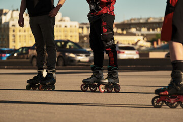 Three men stand on roller skates in the city next to the road.