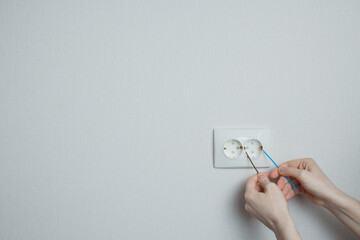 concept of what not to do. dangerous action. the girl inserts two wires into the socket.