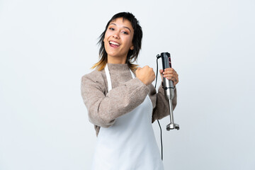 Chef Uruguayan girl using hand blender over isolated white background celebrating a victory
