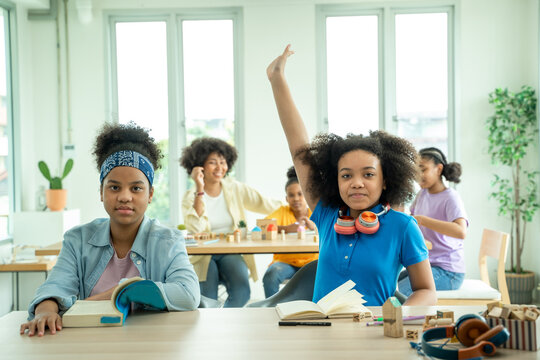 Children In Elementary School Class,African american raised hands up in classroom,Pupils enjoying studying in classroom.