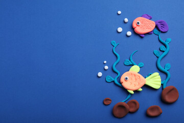 Fototapeta na wymiar Colorful fish, water plants and stones made with play dough on blue background, flat lay. Space for text