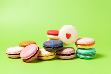 Heap Multi-colored macarons or macaroons with different flavors on green background