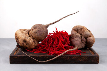 Ugly crooked beetroot on brown chopping board. Vegetables of abnormal shape.  Concept - Using in...