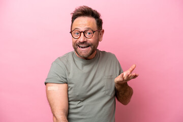 Middle age man wearing a band aids isolated on pink background with shocked facial expression