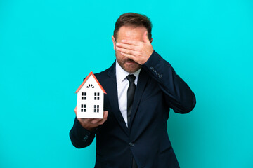 Real estate middle age agent man isolated on blue background covering eyes by hands. Do not want to...