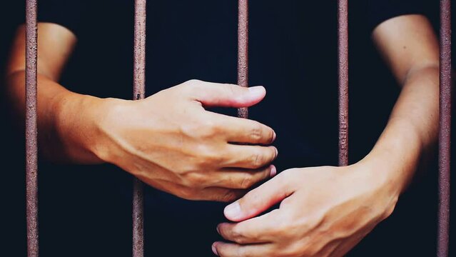 hand man pat steel in jail on black background.concept for prisoner,miserable,abject,rueful
