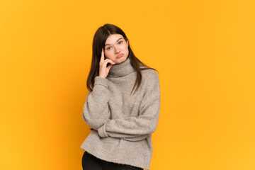 Young Ukrainian girl isolated on yellow background thinking an idea