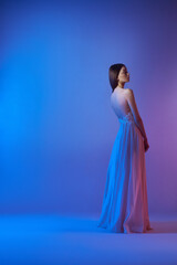 Fototapeta premium Art fashion beautiful elegant woman in blowing flying dress. Freedom concept in neon color light. Fashion style of flowing dress on body woman