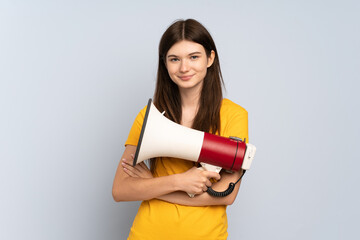 Young Ukrainian girl isolated on white background holding a megaphone and smiling
