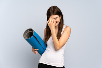 Young Ukrainian sport girl going to yoga classes while holding a mat laughing