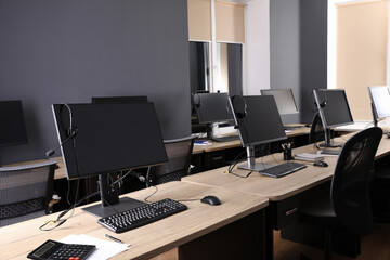 Modern computers with headsets on wooden desk in office. Hotline service