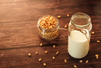 fermented milk product kefir in a glass jar with pine nuts on a beige background