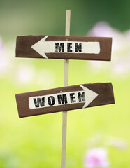 Men-Women way on a wooden signpost on a natural green background.copy space.