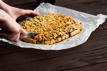 Woman's hands cut fruit pie. Pie on a wooden table.
