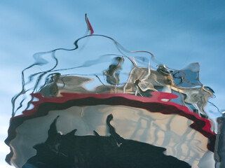 Reflexion and mirroring of a ship in blue water. Abstract distorted boat elements in water. Blue...