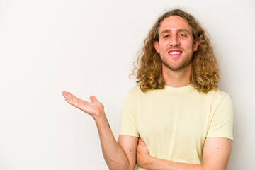 Young caucasian man isolated on white background showing a copy space on a palm and holding another...