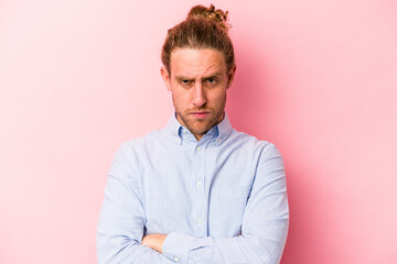 Young caucasian man isolated on pink background frowning face in displeasure, keeps arms folded.