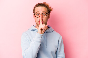 Young caucasian man isolated on pink background keeping a secret or asking for silence.