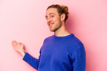 Young caucasian man isolated on pink background showing a welcome expression.
