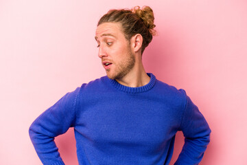 Young caucasian man isolated on pink background laughs happily and has fun keeping hands on stomach.