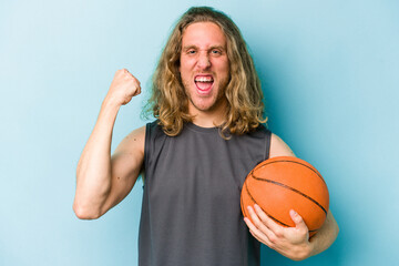 Young caucasian man playing basketball isolated on blue background