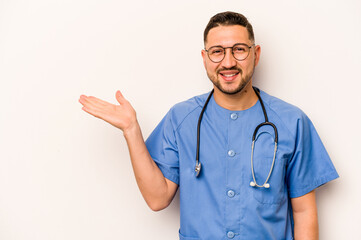 Hispanic nurse man isolated on white background showing a copy space on a palm and holding another hand on waist.