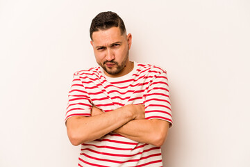 Young hispanic man isolated on white background frowning face in displeasure, keeps arms folded.