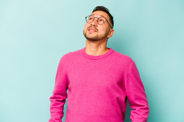 Fototapeta premium Young hispanic man isolated on blue background relaxed and happy laughing, neck stretched showing teeth.