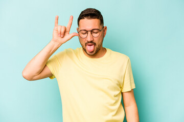 Young hispanic man isolated on blue background showing rock gesture with fingers