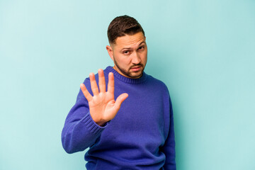 Young hispanic man isolated on blue background rejecting someone showing a gesture of disgust.