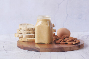 Fototapeta na wymiar almond butter in a container, bread and eggs on table 