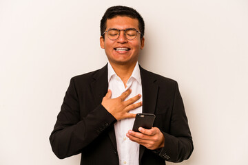 Young business hispanic man holding mobile phone isolated on white background laughs out loudly keeping hand on chest.