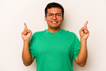 Young hispanic man isolated on white background indicates with both fore fingers up showing a blank space.