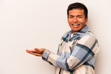 Young hispanic man isolated on white background holding a copy space on a palm.
