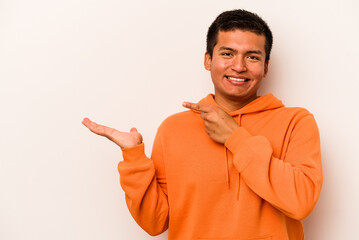 Fototapeta premium Young hispanic man isolated on white background excited holding a copy space on palm.