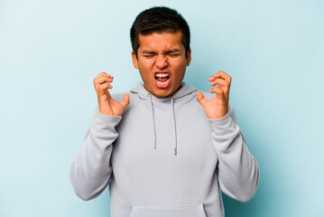 Young hispanic man isolated on blue background screaming with rage.