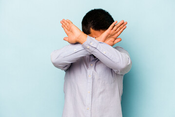 Young hispanic man isolated on blue background keeping two arms crossed, denial concept.