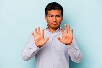 Young hispanic man isolated on blue background rejecting someone showing a gesture of disgust.