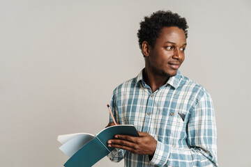 Black unshaven man in plaid shirt writing in exercise book