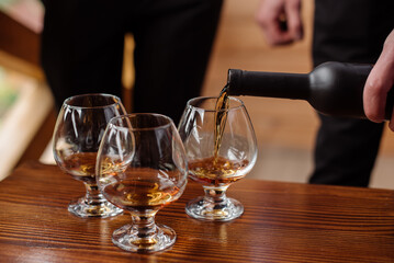 Groom with bestmen drinks whiskey from glasses. Closeup
