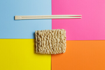 instant noodles and chopsticks on a bright trendy background.