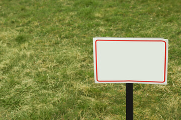 White blank signboard on green grass. Space for text