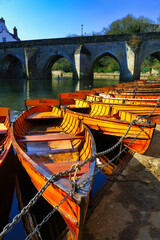 Rowing Boats moored along the river bank with Elvet Bridge in the background. Durham City, County Durham, England, UK.