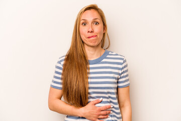 Fototapeta premium Young caucasian woman isolated on white background touches tummy, smiles gently, eating and satisfaction concept.