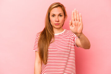 Young caucasian woman isolated on pink background standing with outstretched hand showing stop sign, preventing you.